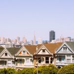 une-rangee-de-maisons-avec-une-ville-en-arriere-plan-YrxIh0LqceA